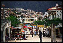 A pedestrian market in the old city, with mountains rising in the background.